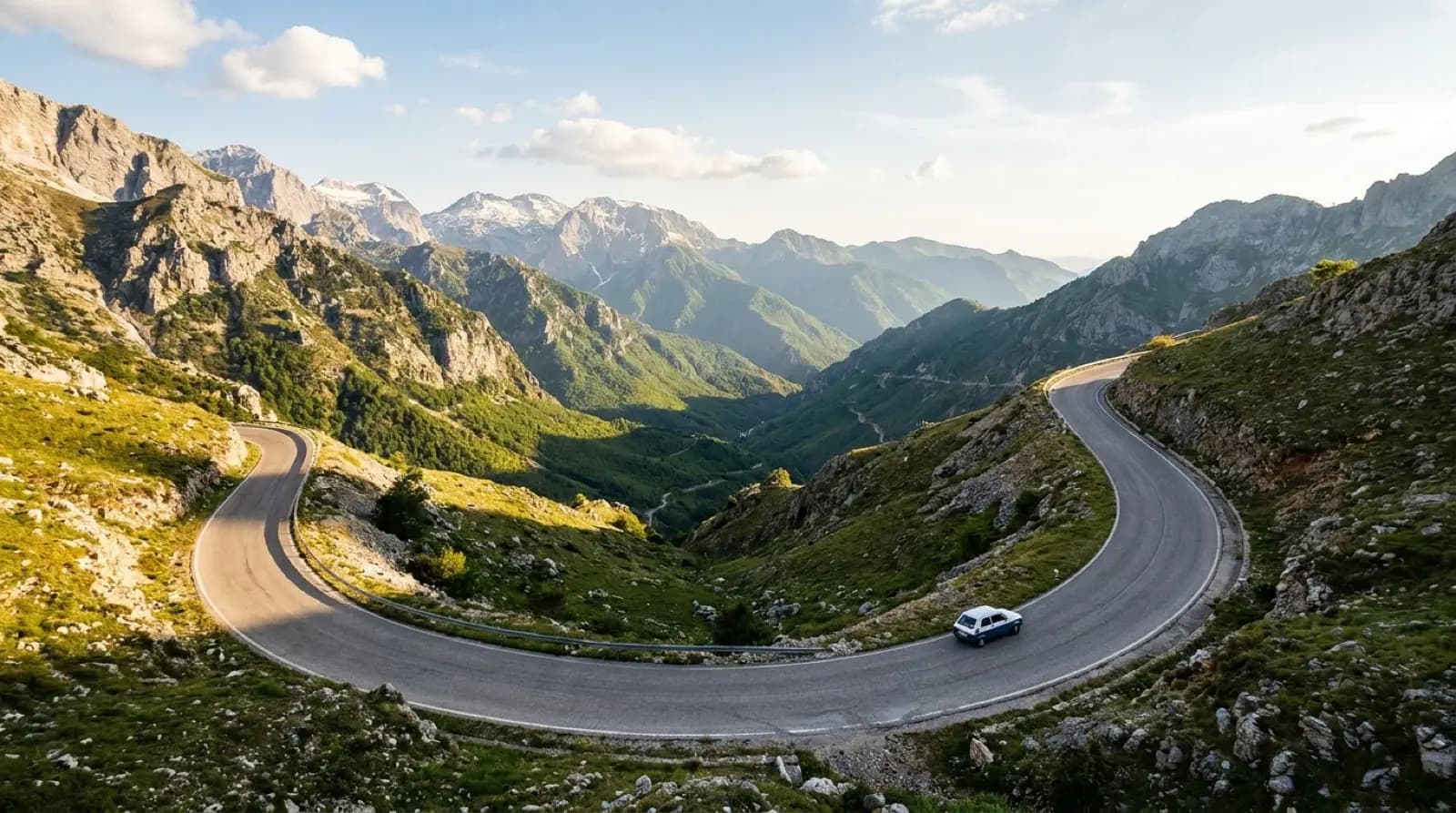 Car driving a scenic mountain road in Albania with valley views in the distance