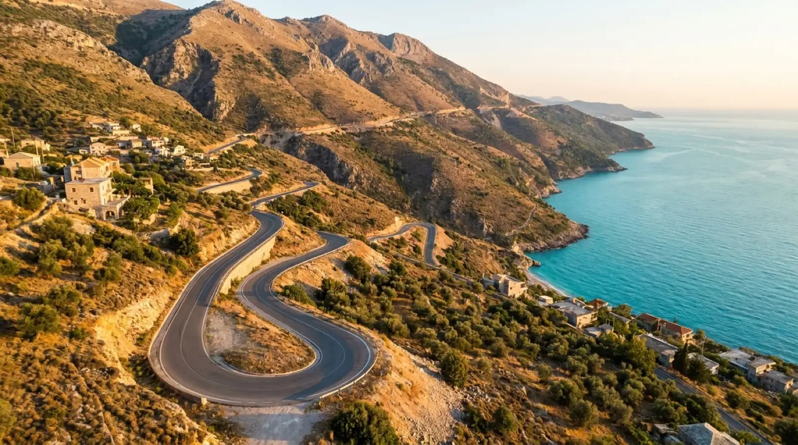 Coastal road winding along the Albanian Riviera between mountains and turquoise sea